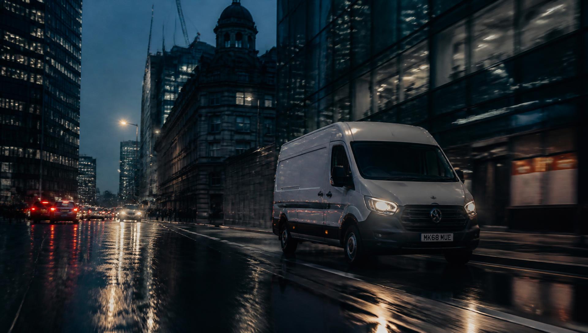 Delivery van driving through a Manchester city street at dusk